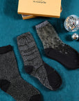 3 paires de chaussettes transparentes à paillettes argentées Atelier St Eustache posées à plat à côté du coffret de Noël dans une ambiance hivernale