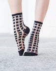 chaussettes transparentes à carreaux noirs pied pointé sur fond gris