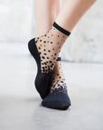 Chaussettes transparentes à pois noirs, portées par une femme debout
