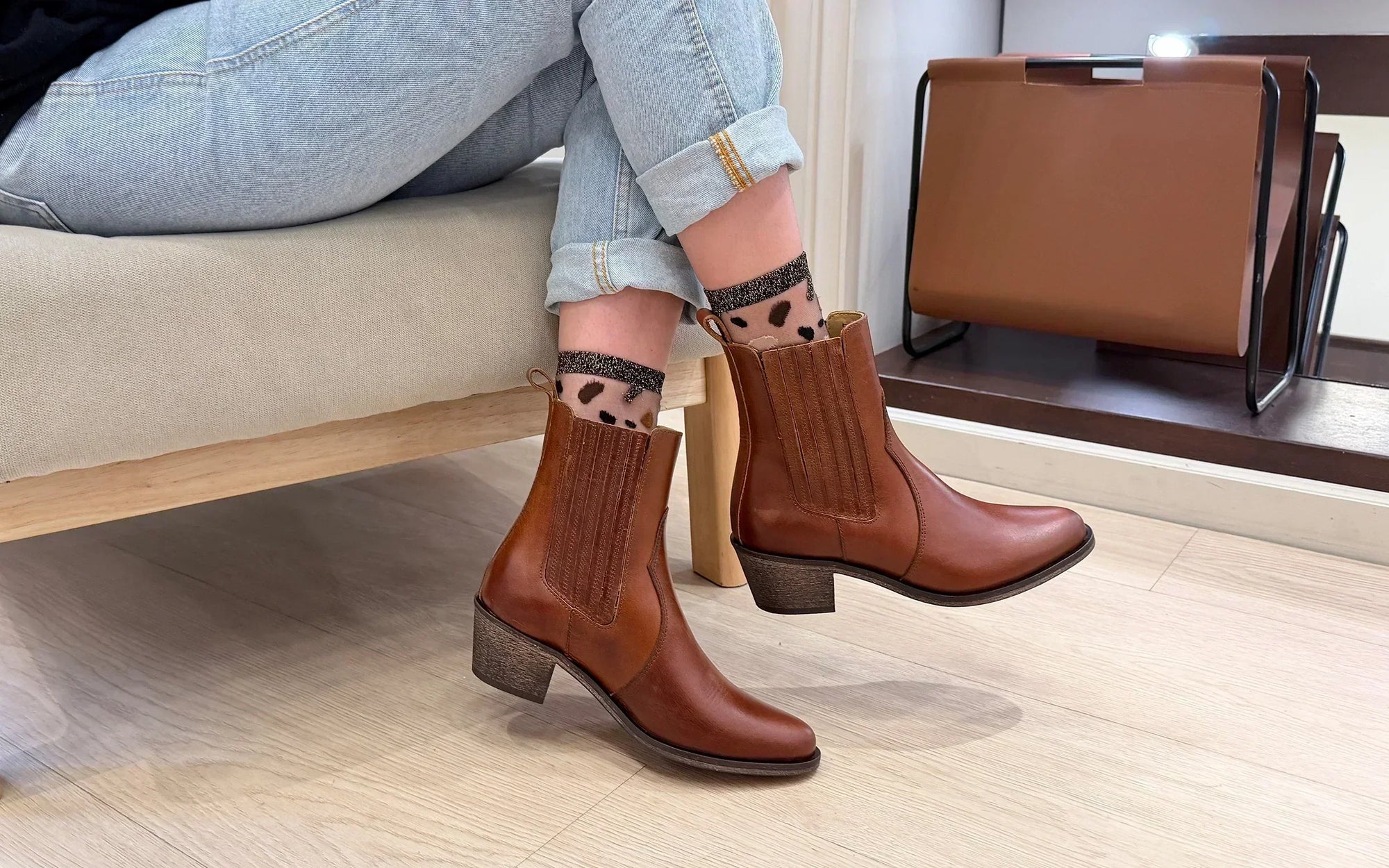 Photo d’une femme portant des chaussettes transparentes tachetées de marron, beige et noir, rehaussées de finitions dorées pailletées.