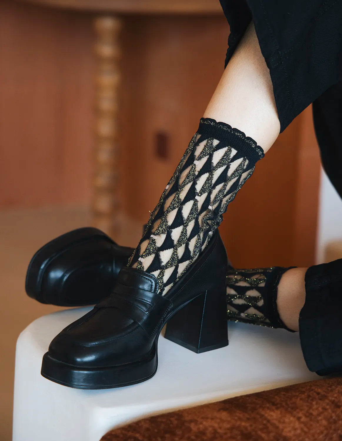Zoom de la paire de chaussettes transparentes à paillettes dorées Arlecchino Dorée Atelier St Eustache portée par une mannequin avec des chaussures à talons noires