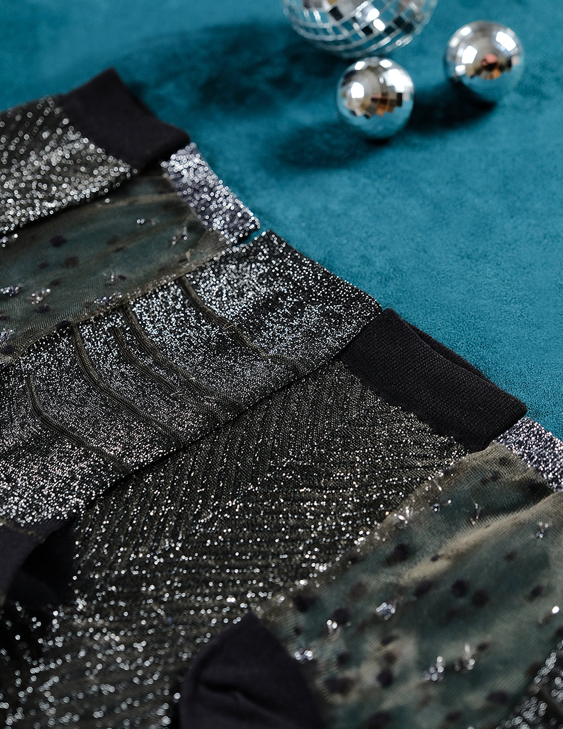 Paires de chaussettes transparentes à paillettes du coffret Noël argenté Atelier St Eustache dépliées posées à plat dans une ambiance hivernale et festive