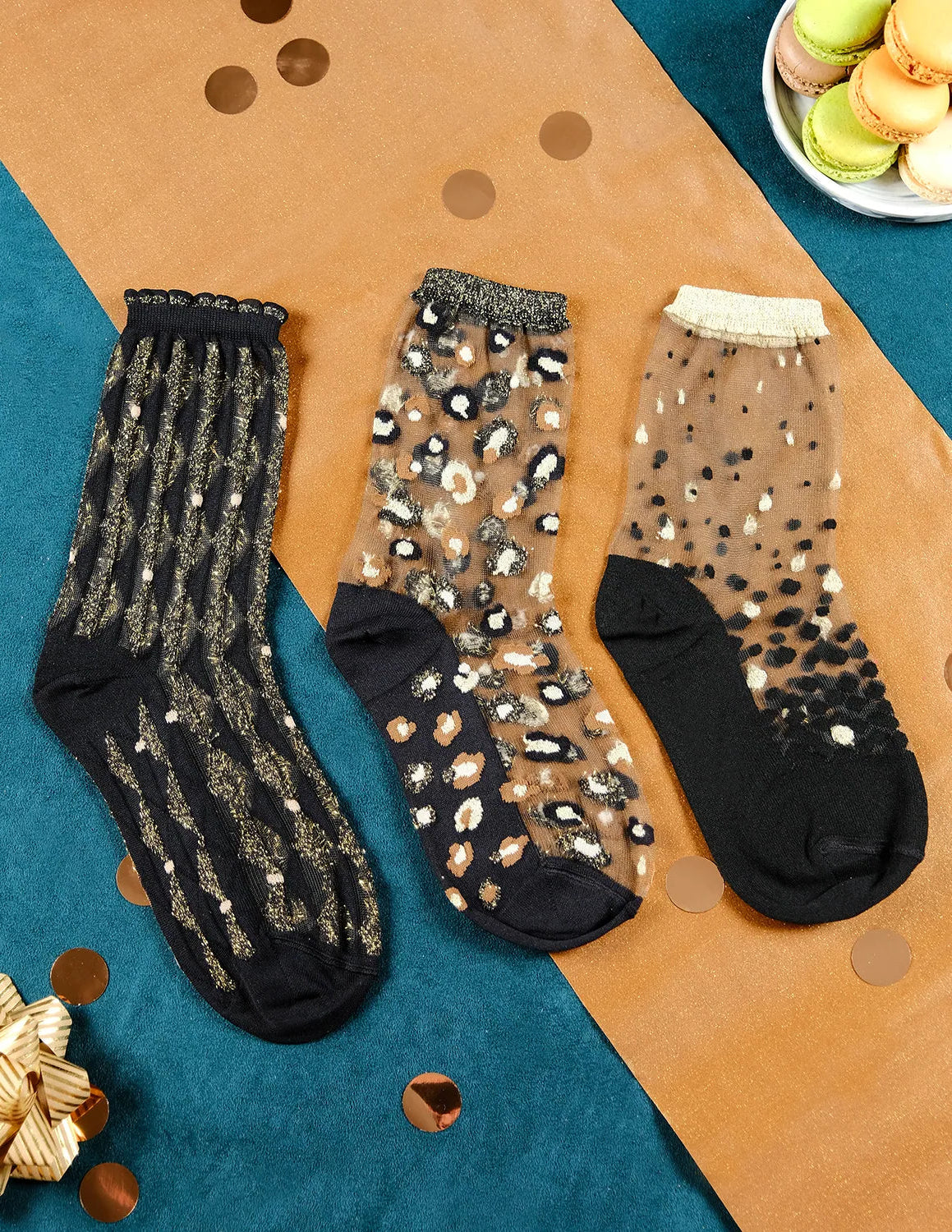 3 paires de chaussettes transparentes à paillettes dorées Atelier St Eustache posées à plat dans une ambiance festive et lumineuse pour Noël