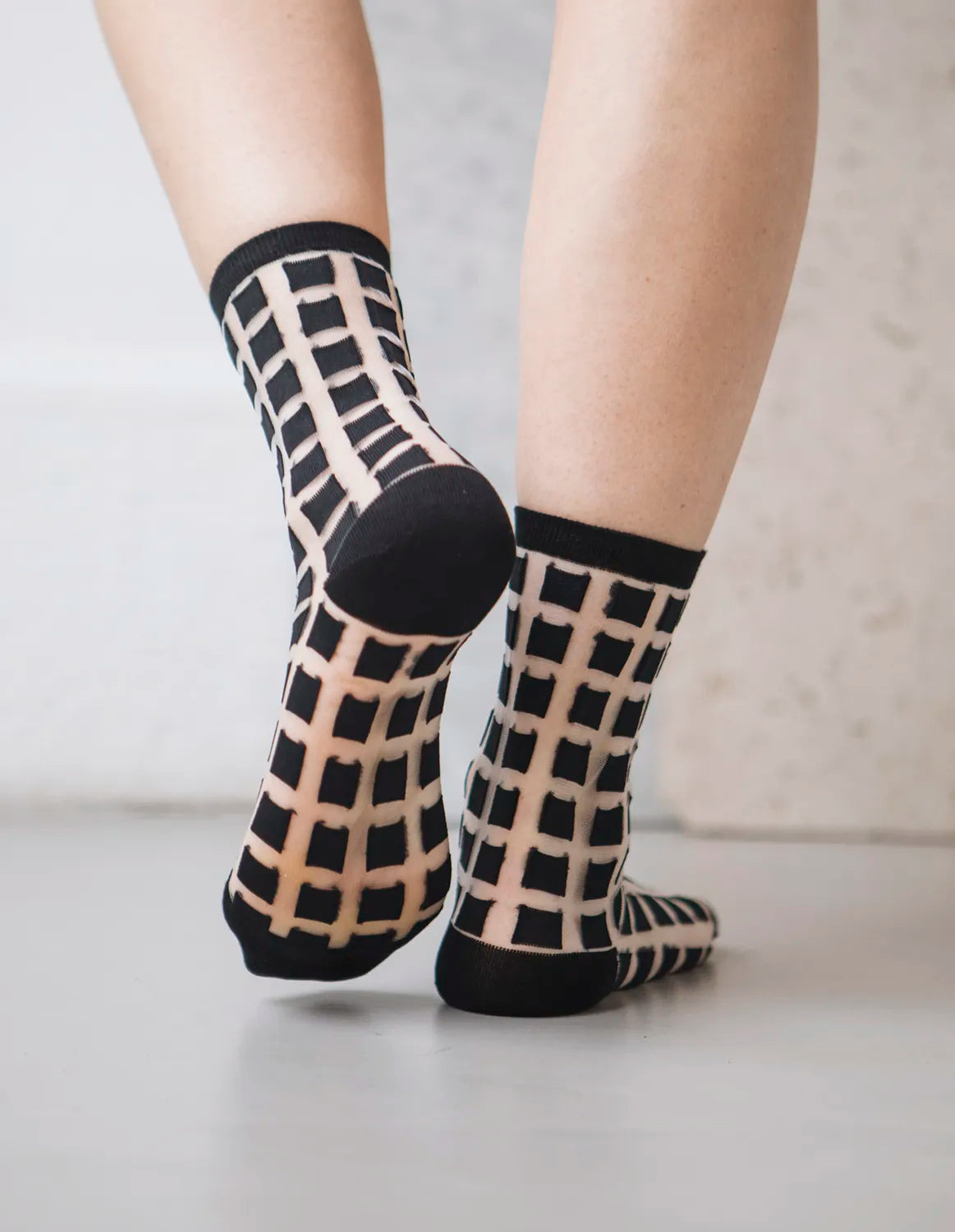 chaussettes transparentes à carreaux noirs pied relevé fond gris