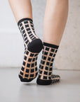chaussettes transparentes à carreaux noirs pied relevé fond gris
