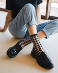 chaussettes transparentes à carreaux noirs et chaussures mocassins noirs jambes croisées jean bleu clair ambiance décontractée