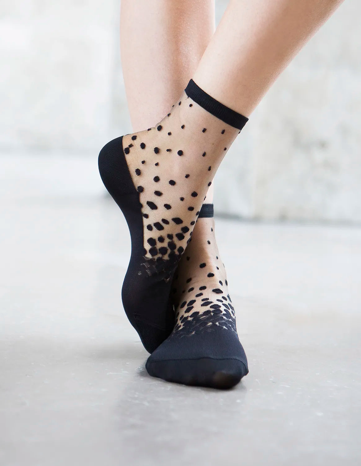 Chaussettes transparentes à pois noirs, portées par une femme debout